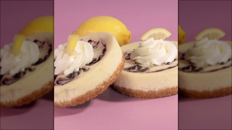 Two Crumbl Lemon Blueberry Cheesecakes on a pink background
