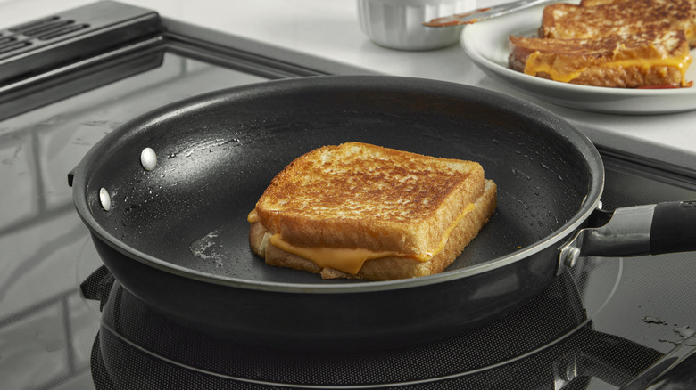 A grilled cheese sandwich cooking in a pan on a stovetop