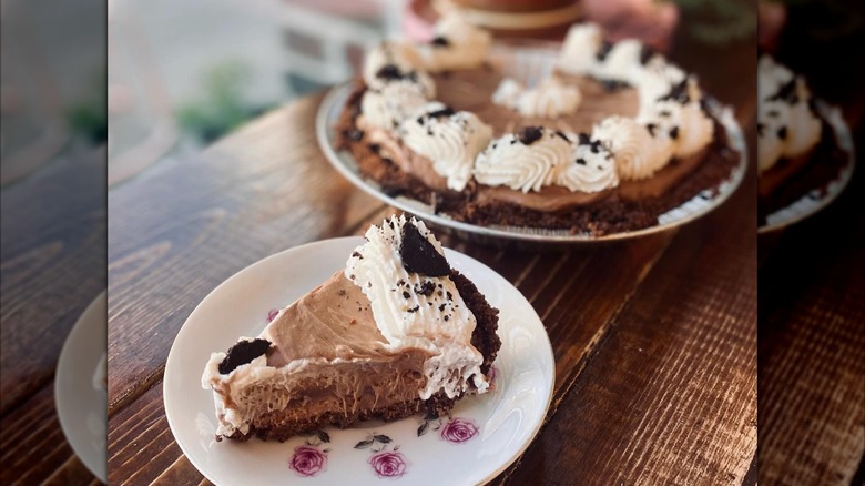Slice of chocolate pie in front of whole pie on wooden counter