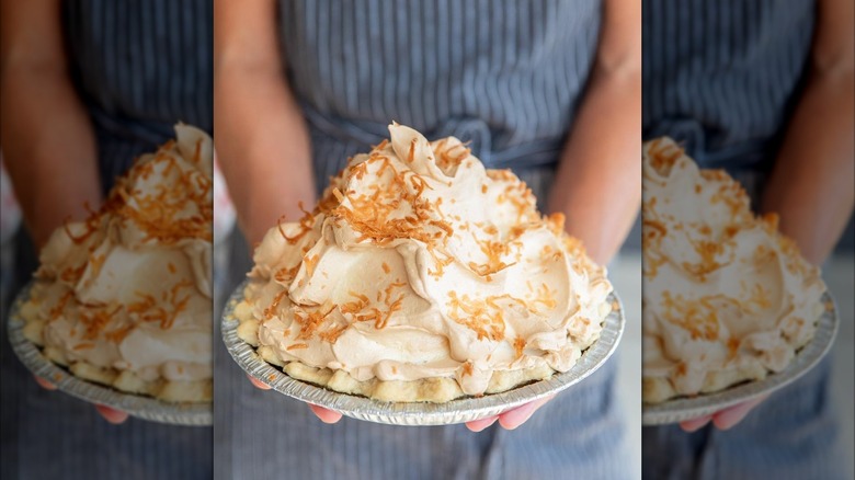 Two hands holding tall meringue pie
