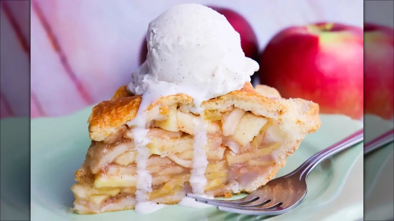 Close-up of apple pie with ice cream on top on green plate