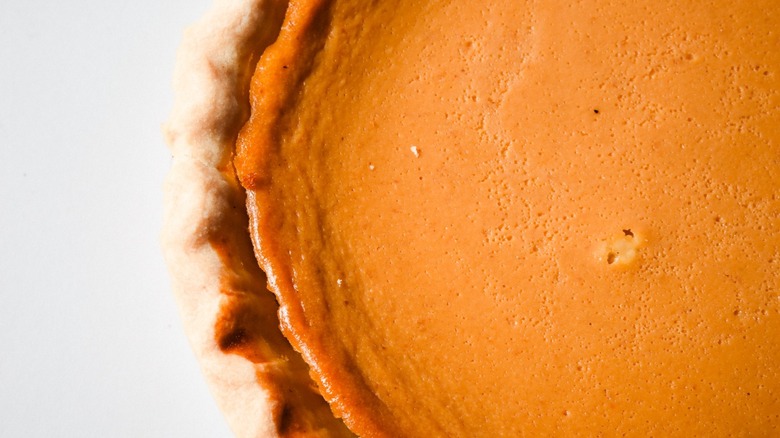 Close-up of pumpkin pie half on white background