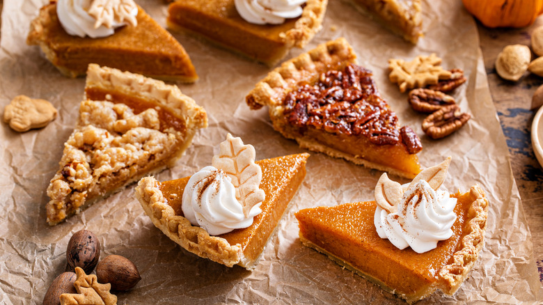 Slices of pecan, crumble, and pumpkin pie on parchment paper