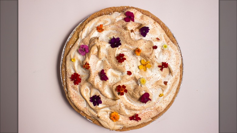 Top-down of cream pie with decorative flowers on top on white background