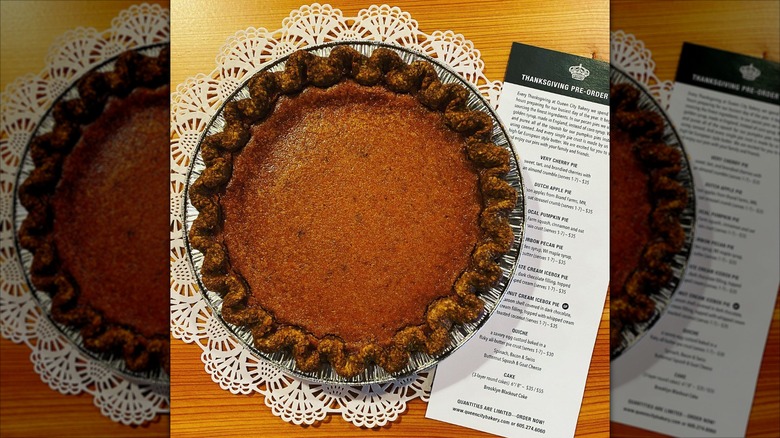 Top-down shot of pumpkin pie next to pie menu on doily