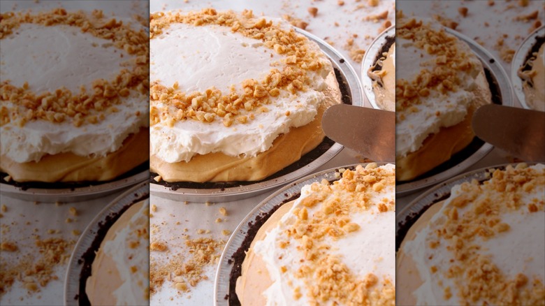 Two peanut butter pies with crushed peanut and whipped cream topping on white table