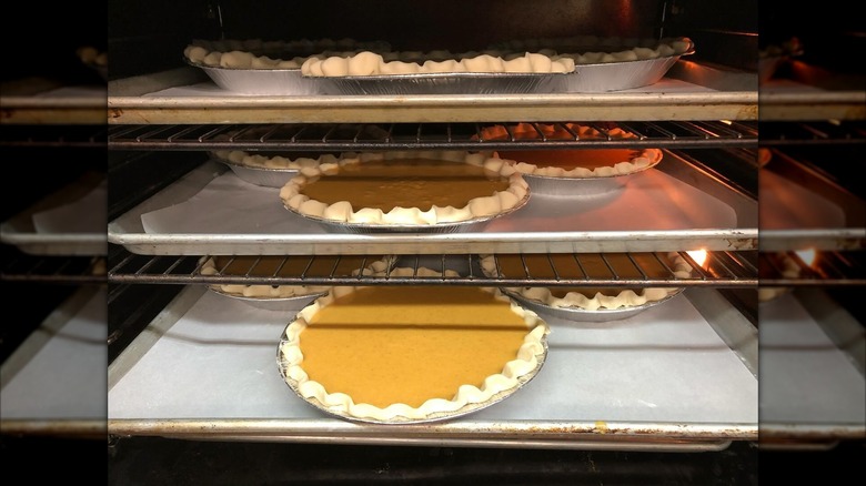 Pumpkin pies baking on racks in oven