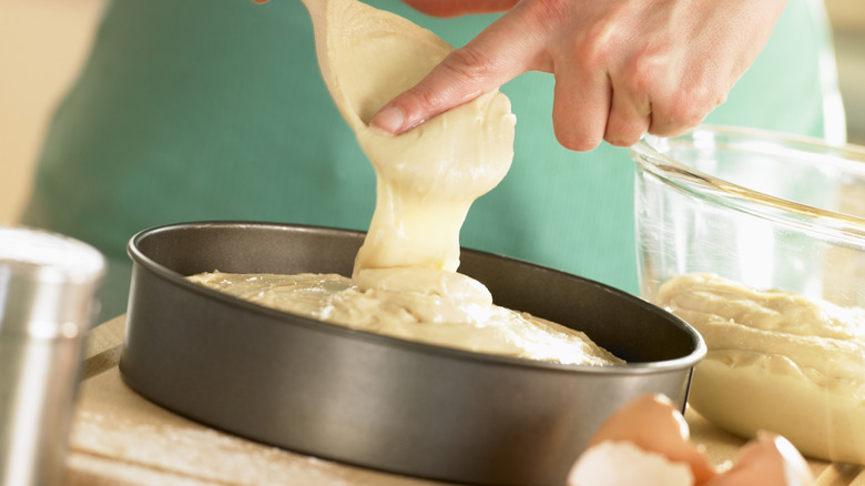 A person spooning cake batter into a pan