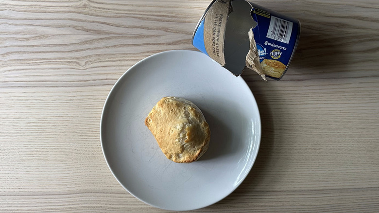 An empty can of Pillsbury Grands! Southern Homestyle Buttermilk Biscuits next to a baked biscuit on a plate