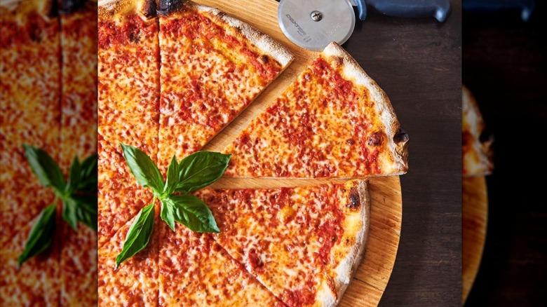 L'Industrie pizzas on a wooden board with a pizza cutter next to them