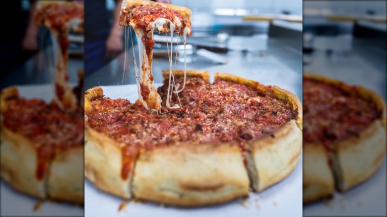 Hand lifting a slice out of a deep dish pizza