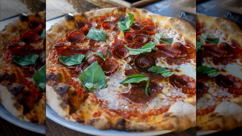 Pizza with pepperoni and fresh basil leaves