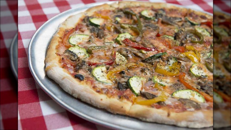Veggie pizza on tray on red and white checked tablecloth