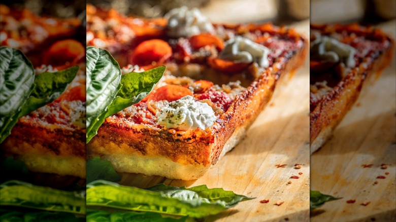 Close-up of the corner of Detroit-style pizza with gresh basil