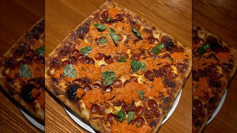 Square pizza with pepperoni, basil, and vodka sauce drizzle