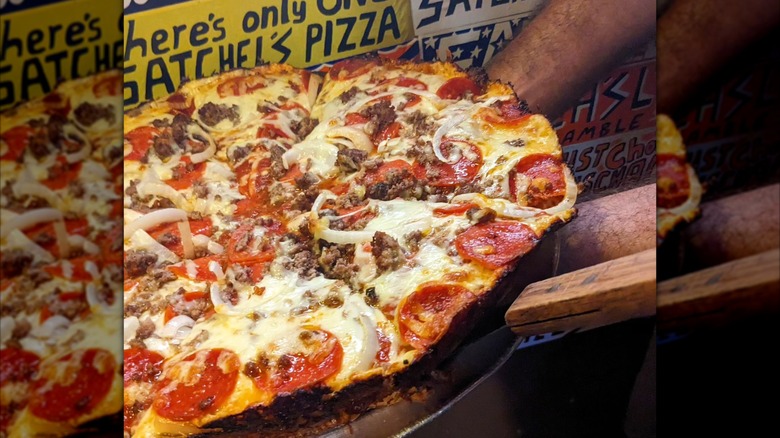 Pepperoni pizza on a tray in front of Satchel's sign