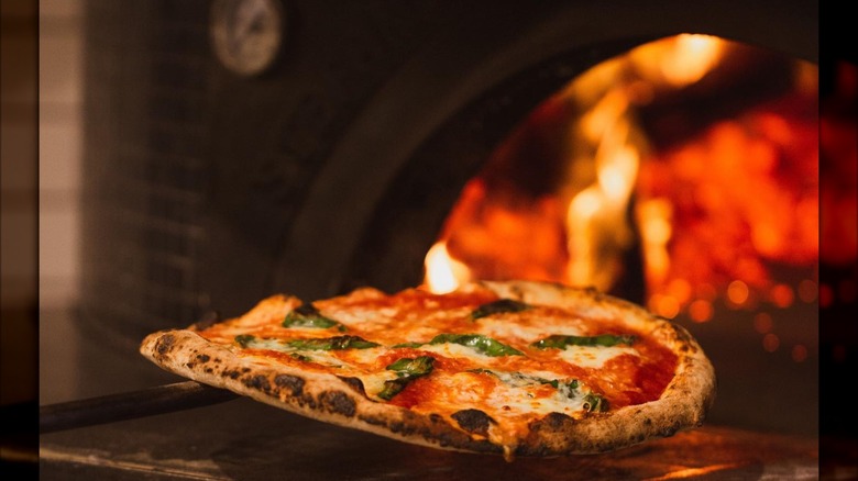 Pizza being put into a wood-fired oven