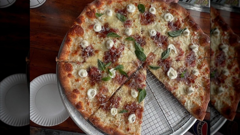 Top-down New York-style pizza on tray with slice missing