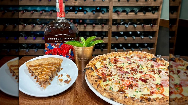 Whole pizza and slice of dessert pizza with bottle of Woodford Reserve and minty cocktail