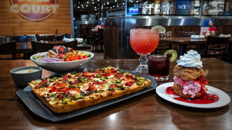 Detroit-style pizza with dessert, cocktails, and salad on a table in restaurant