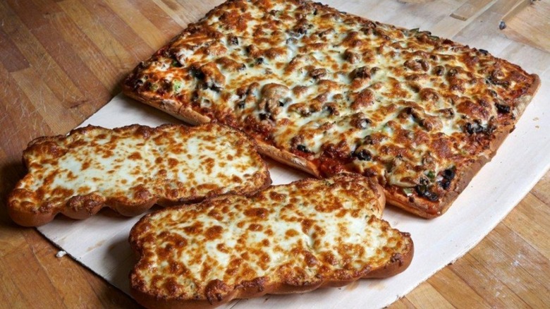Pizza and cheesy garlic bread on wooden table