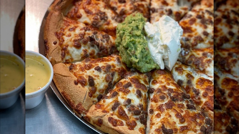 Thick-crust cheese pizza with guacamole and sour cream in the middle