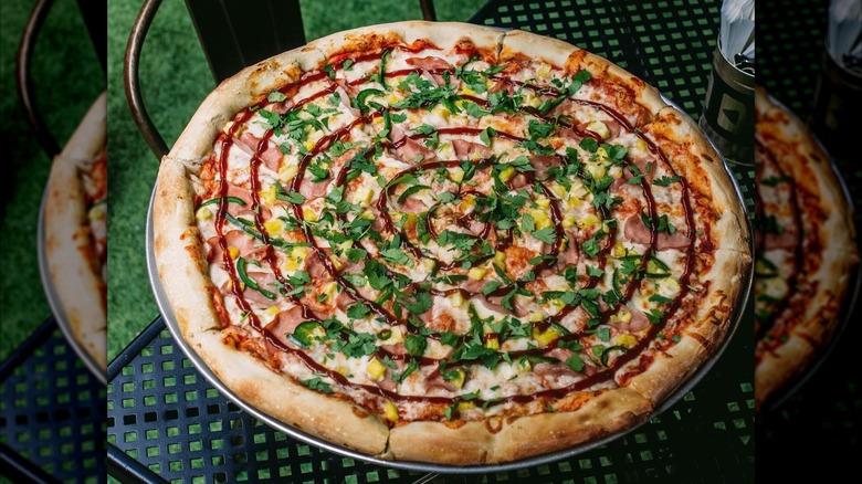 Ham and pineapple pizza on a metal table outside