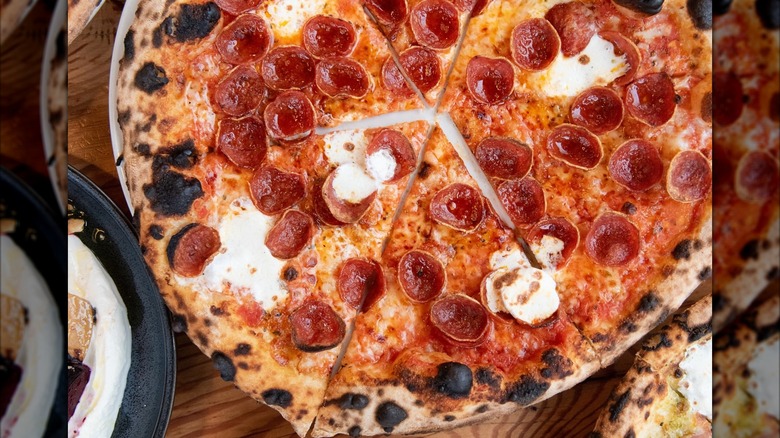 Wood-fired New York-style pizza sliced with pepperoni