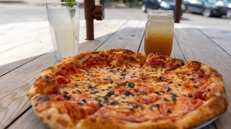 Pizza on picnic table outside with two cocktails