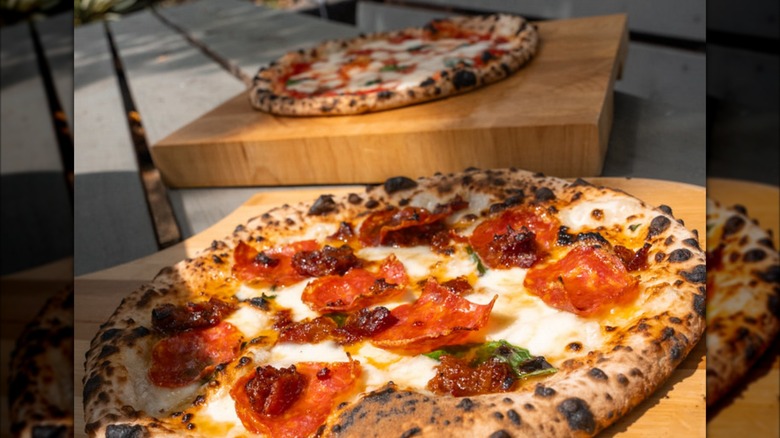 Two wood-fired pizzas on a table outside