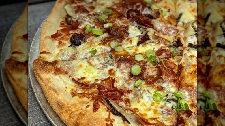 Close-up of pizza with scallions, apples, and cheese