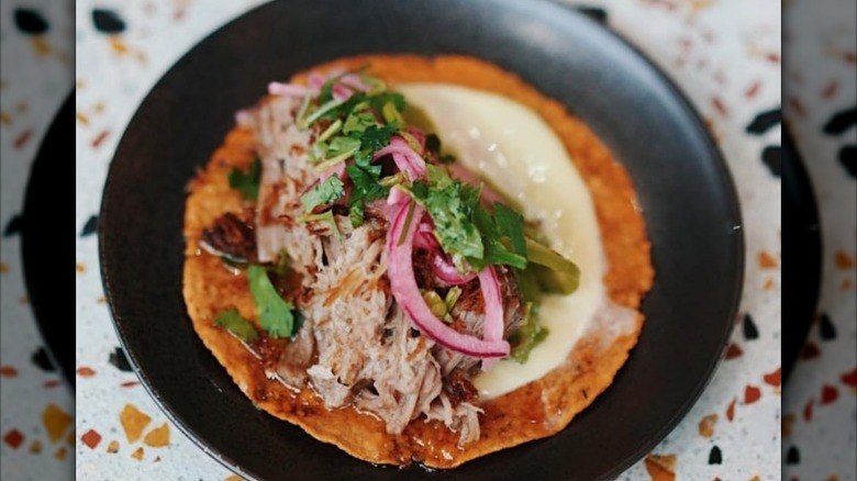 Lola 55 taco with onion cilantro black plate