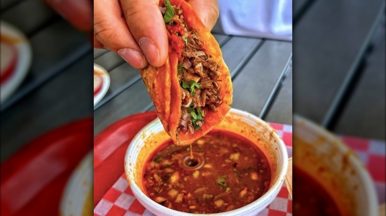 birria taco dunked into caldo broth