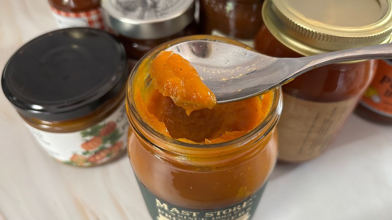 Spoon holding scoop of pumpkin butter over jar of pumpkin butter