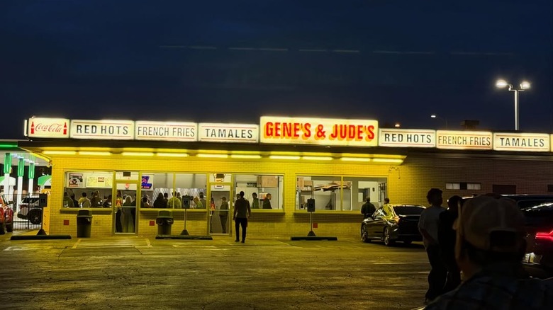 The exterior of Gene and Jude's after dark, with its sign advertising red hots, French fries, and tamales