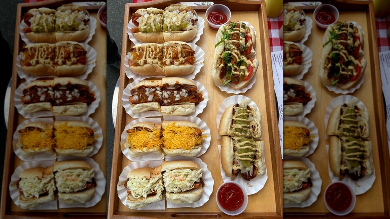 Seven loaded hot dogs on wooden tray cut in half served at Super Duper Weenie
