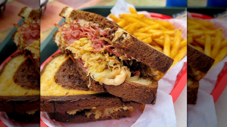 Close-up of a corned beef on rye sandwich, fries in the background