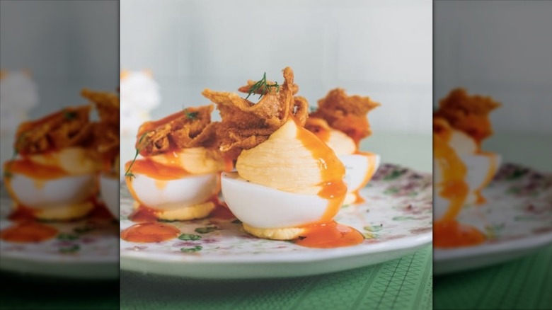Deviled eggs with fried chicken skin on floral plate served at Turkey and the Wolf