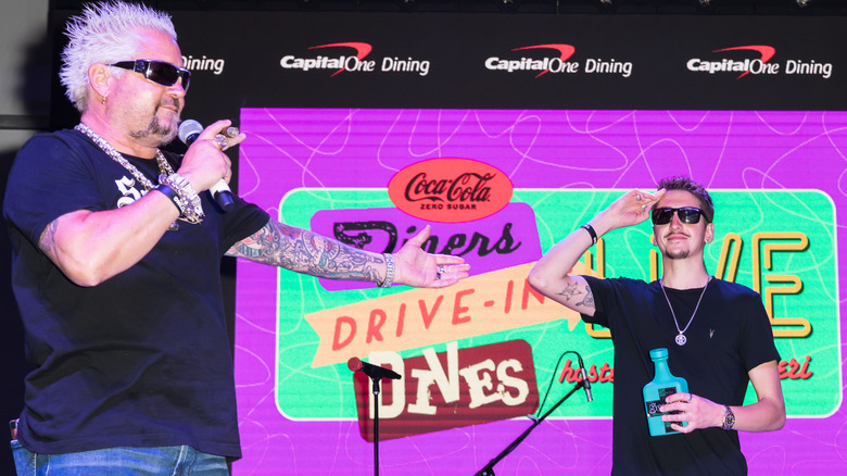Guy Fieri in front of Diners, Drive-Ins & Dives banner