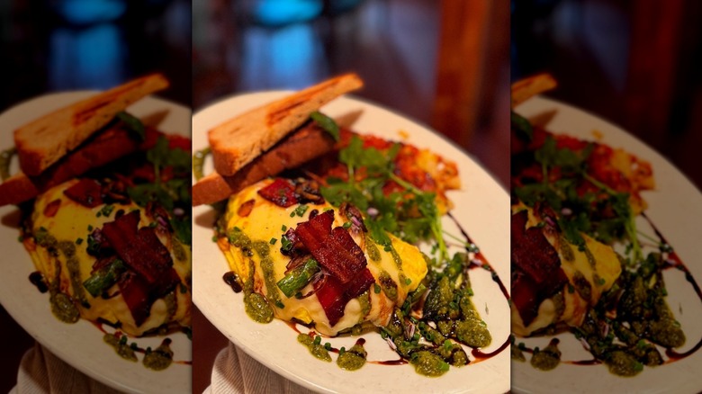 Close-up of omelette with asparagus and bacon on white plate, toast behind