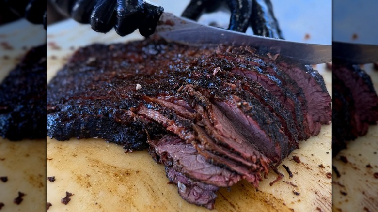 Close-up of hand slicing meat on cutting board