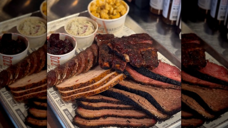 Sliced barbecued meats on tray, mac and cheese, mashed potatoes behind
