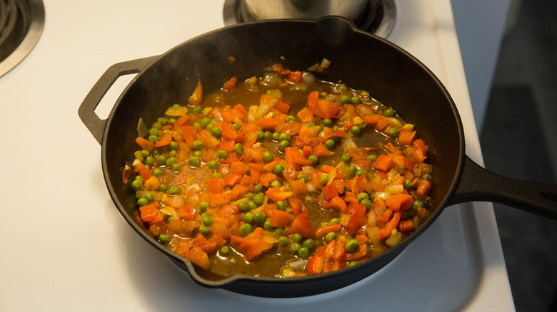 vegetables sauteing in iron pan