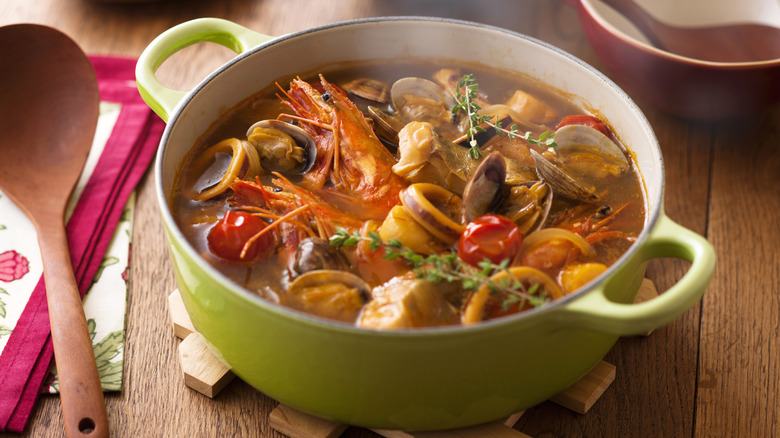 Pot of bouillabaisse beside a wooden spoon