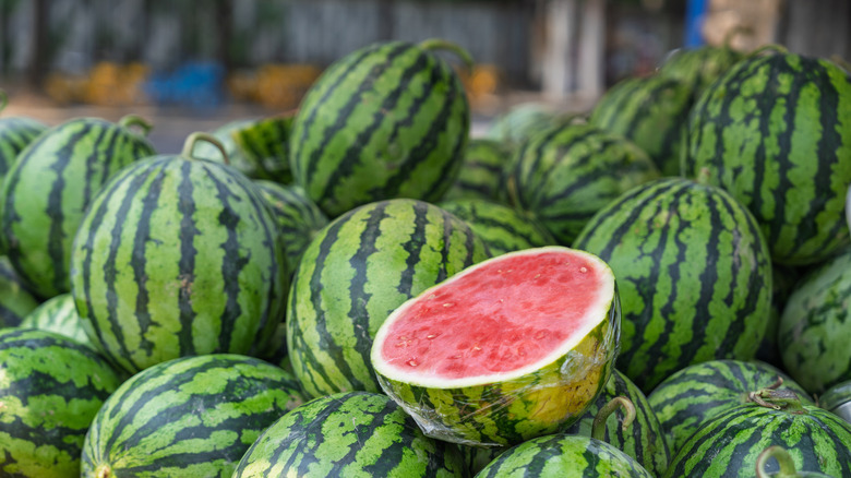 A display of fresh watermelons with one fruit cut in half