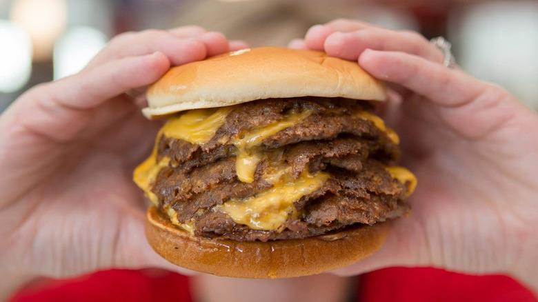 A person holding a 7x7 Burger from Steak n' Shake