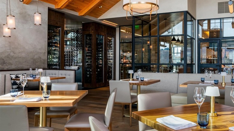 Restaurant dining room with set tables, elegant light fixtures, and wine selection