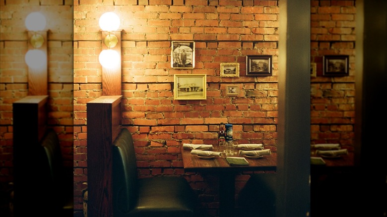 Green restaurant booth against a brick wall with hanged vintage art