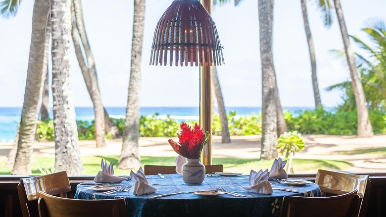 Set restaurant table with Hawaiian beach and trees backdrop