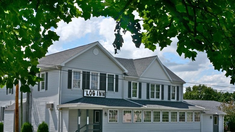 Exterior view of The Log Inn framed by a tree
